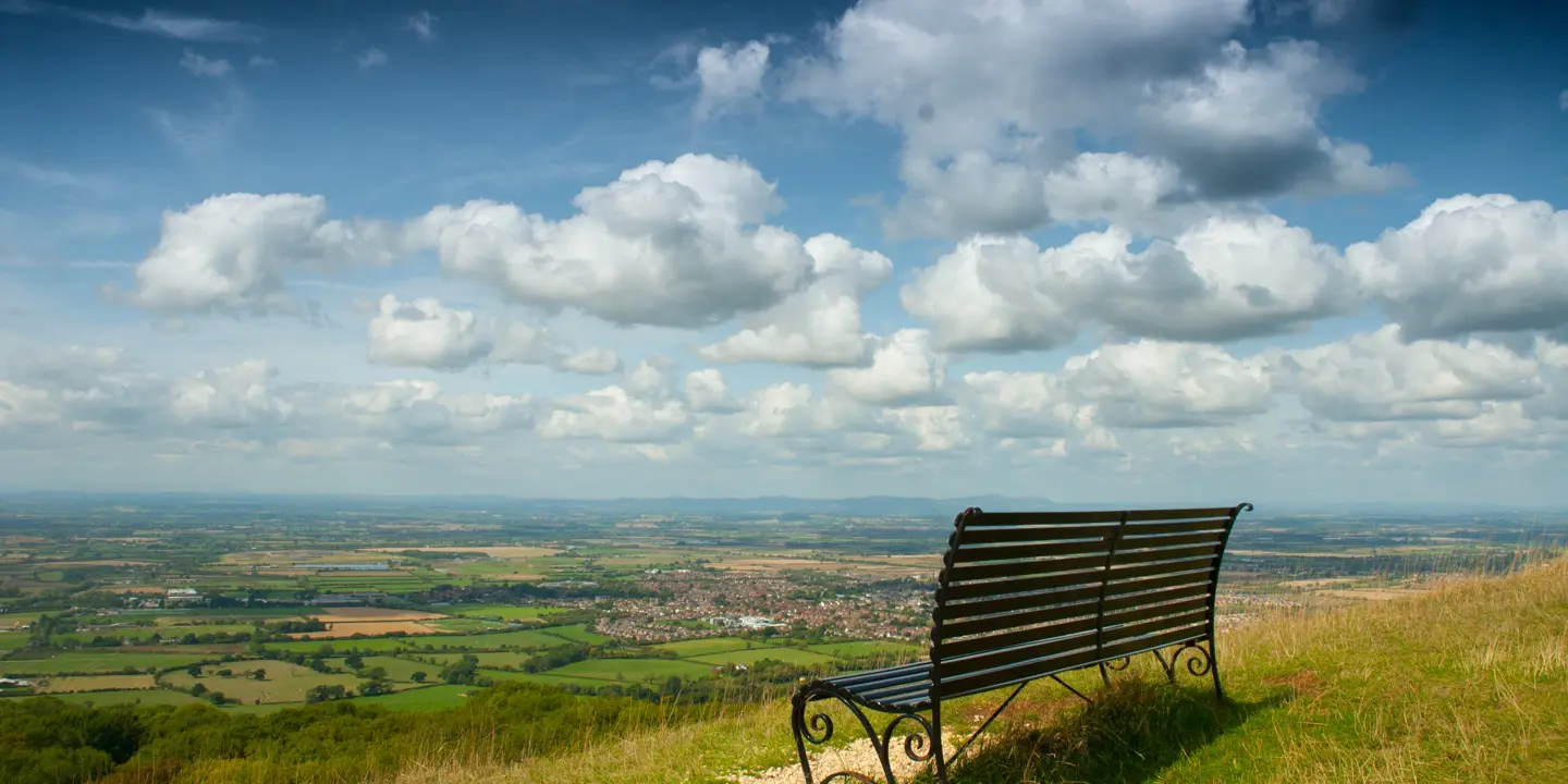 A wooden bench resting atop a verdant hillside.
