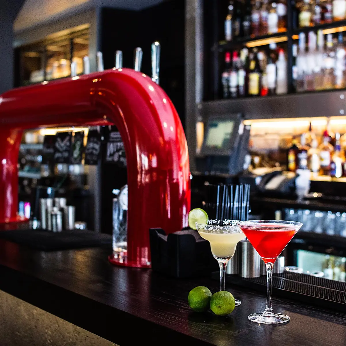 Two cocktail glasses placed on a bar counter with slices of lime.