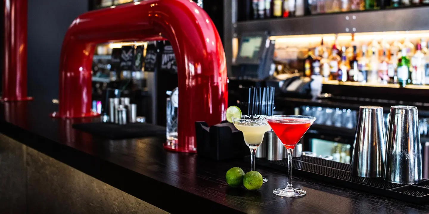 Two cocktail glasses placed on a bar counter with slices of lime.