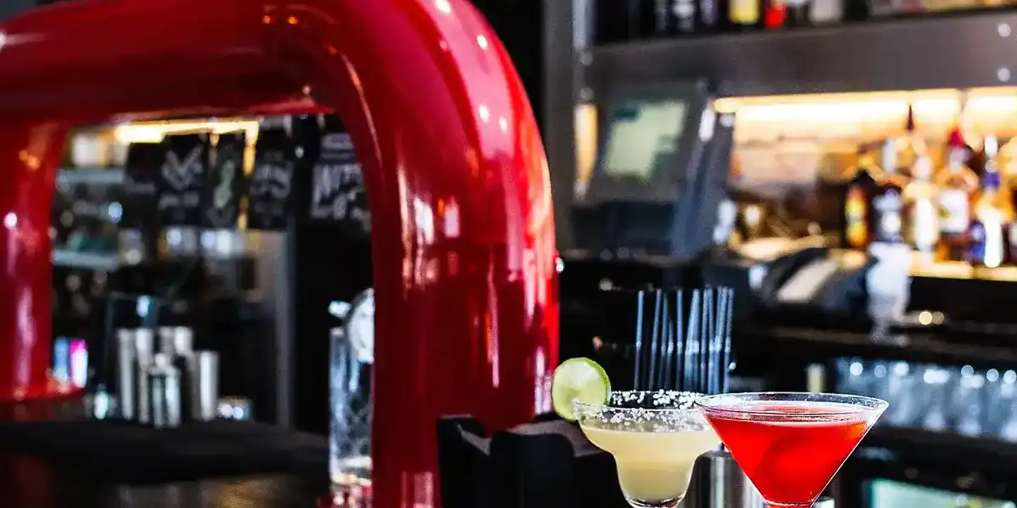 Two cocktail glasses placed on a bar counter with slices of lime.