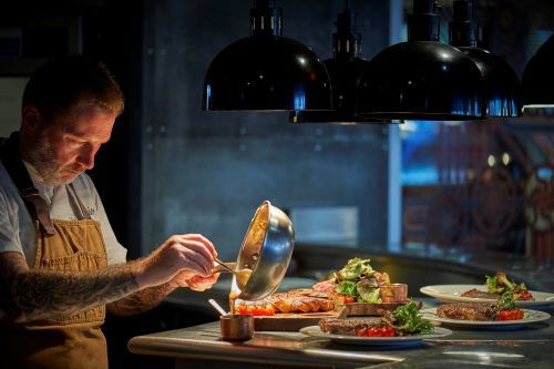 A Chef preparing a meal to go out from the kitchen