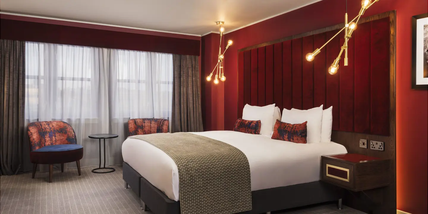 Spacious room featuring a comfy bed and armchairs