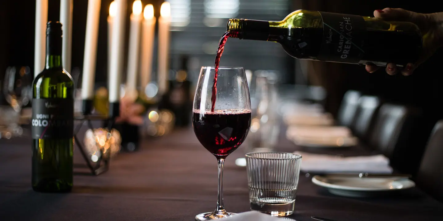 A person pouring wine into a glass.