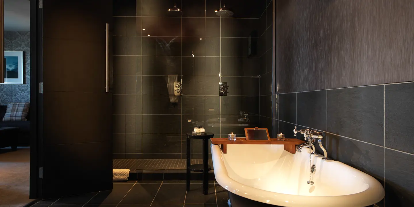 Black and white bathtub positioned in a bathroom alongside a walk-in shower.