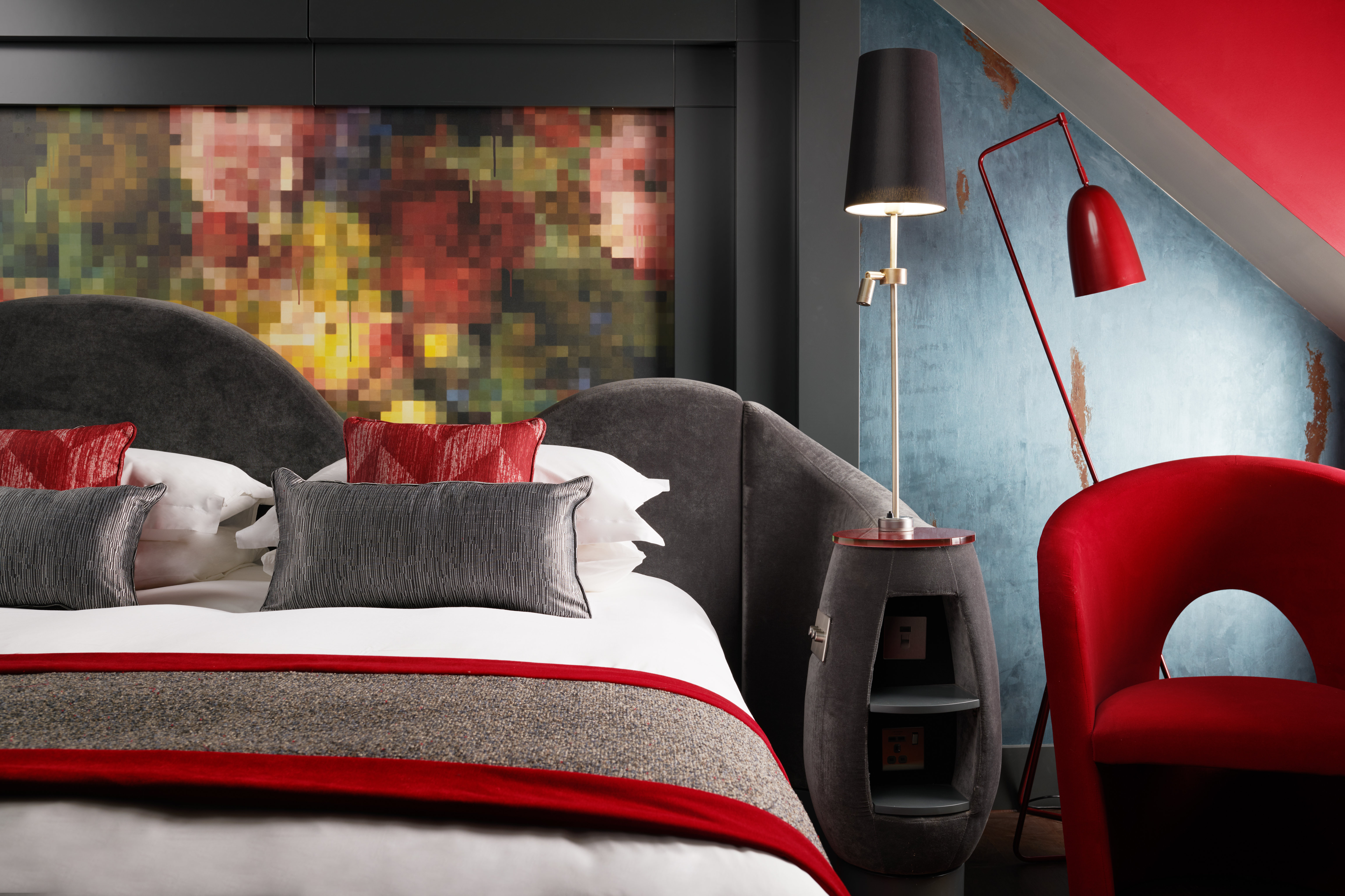 Bedroom featuring a comfortable bed and a vibrant red chair.