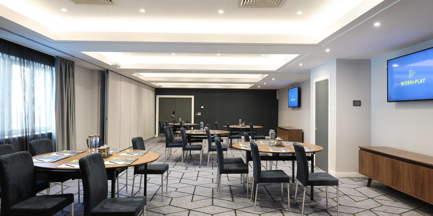 Air conditioned conference room featuring multiple tables, chairs, and flat-screen TVs.