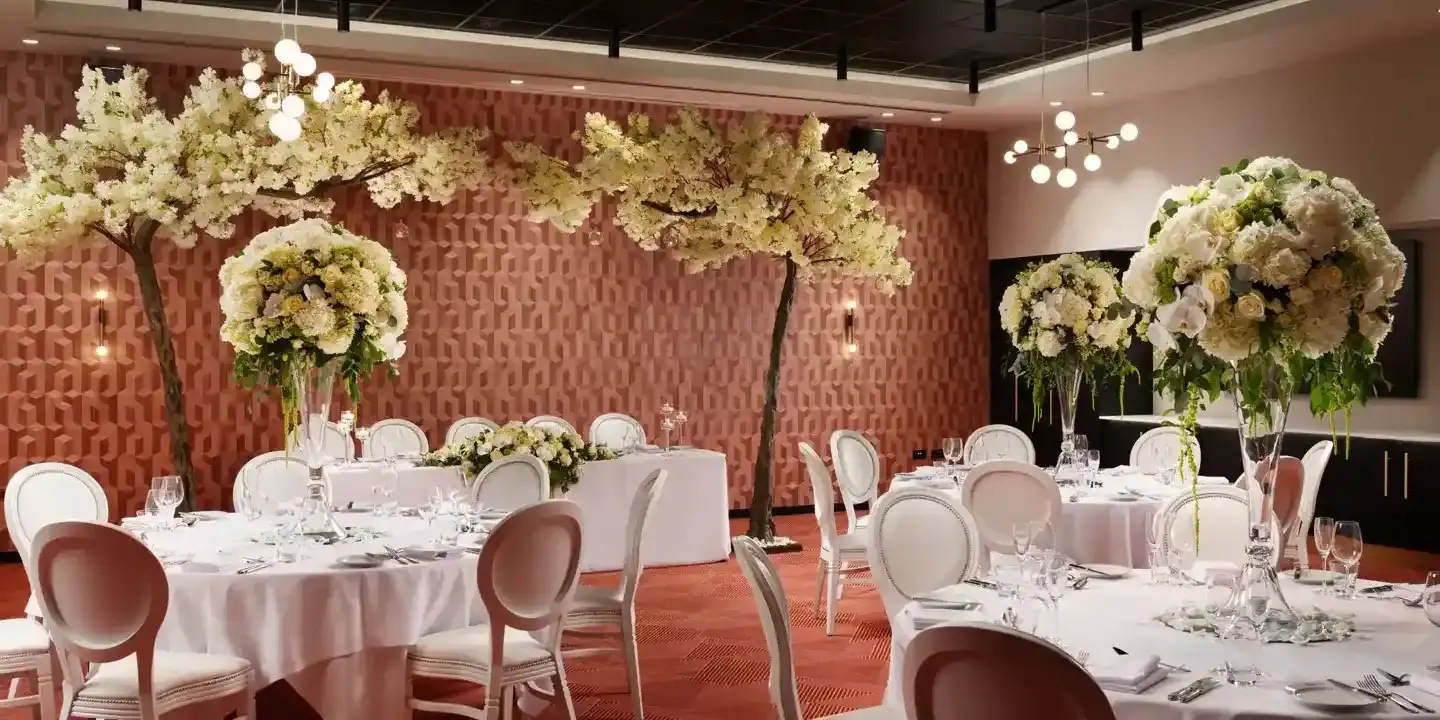An elegantly decorated banquet room featuring pristine white tables and chairs.