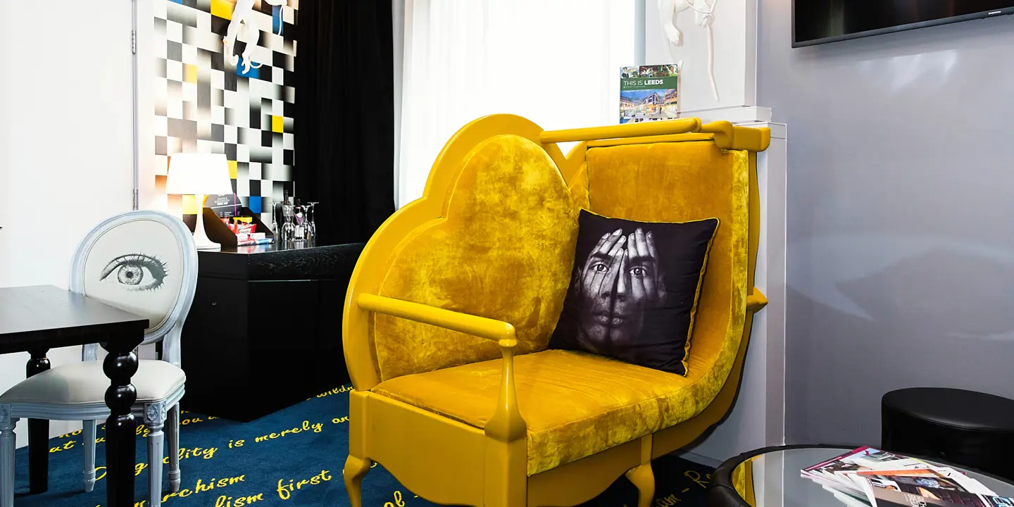A yellow chair positioned in a room adjacent to a window.