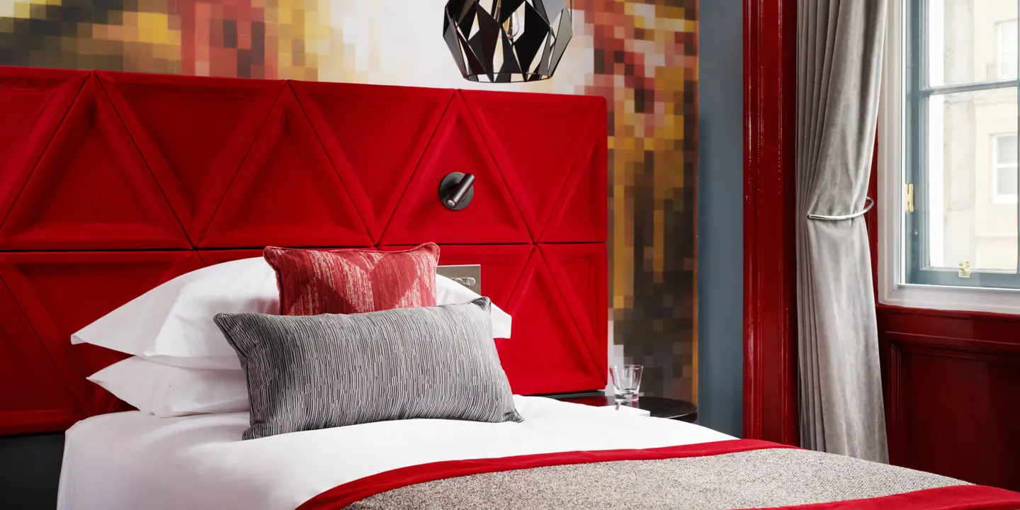 A bed featuring a vibrant red headboard and matching pillows.