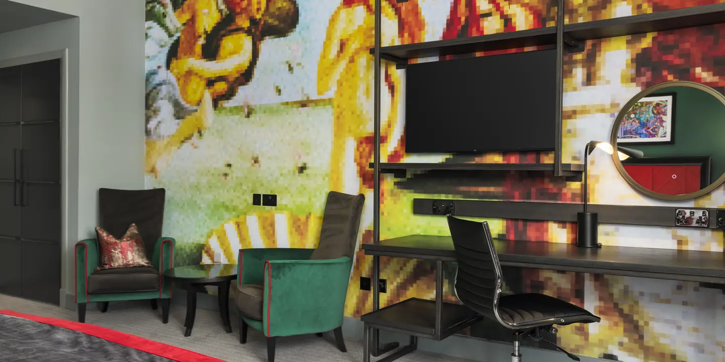 An elegantly furnished hotel room featuring a comfortable armchairs and a stylish desk and chair.