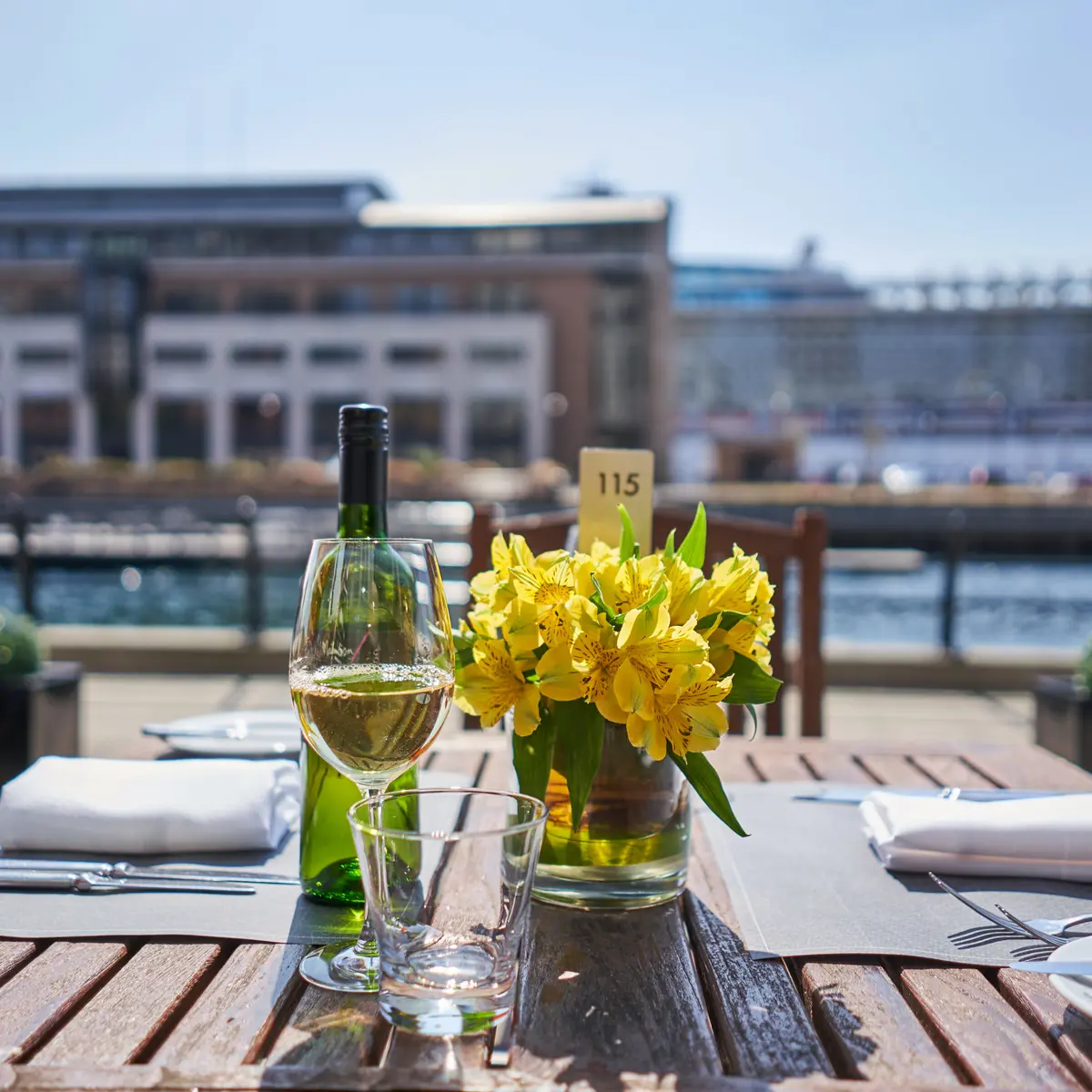 Outdoor table featuring a wine glass and a vase with flowers.