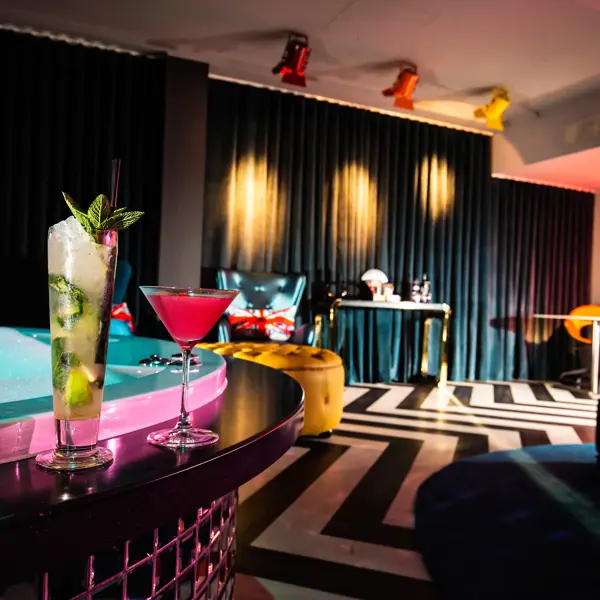 An elegantly furnished room featuring a luxurious hot tub and two refreshing cocktails.