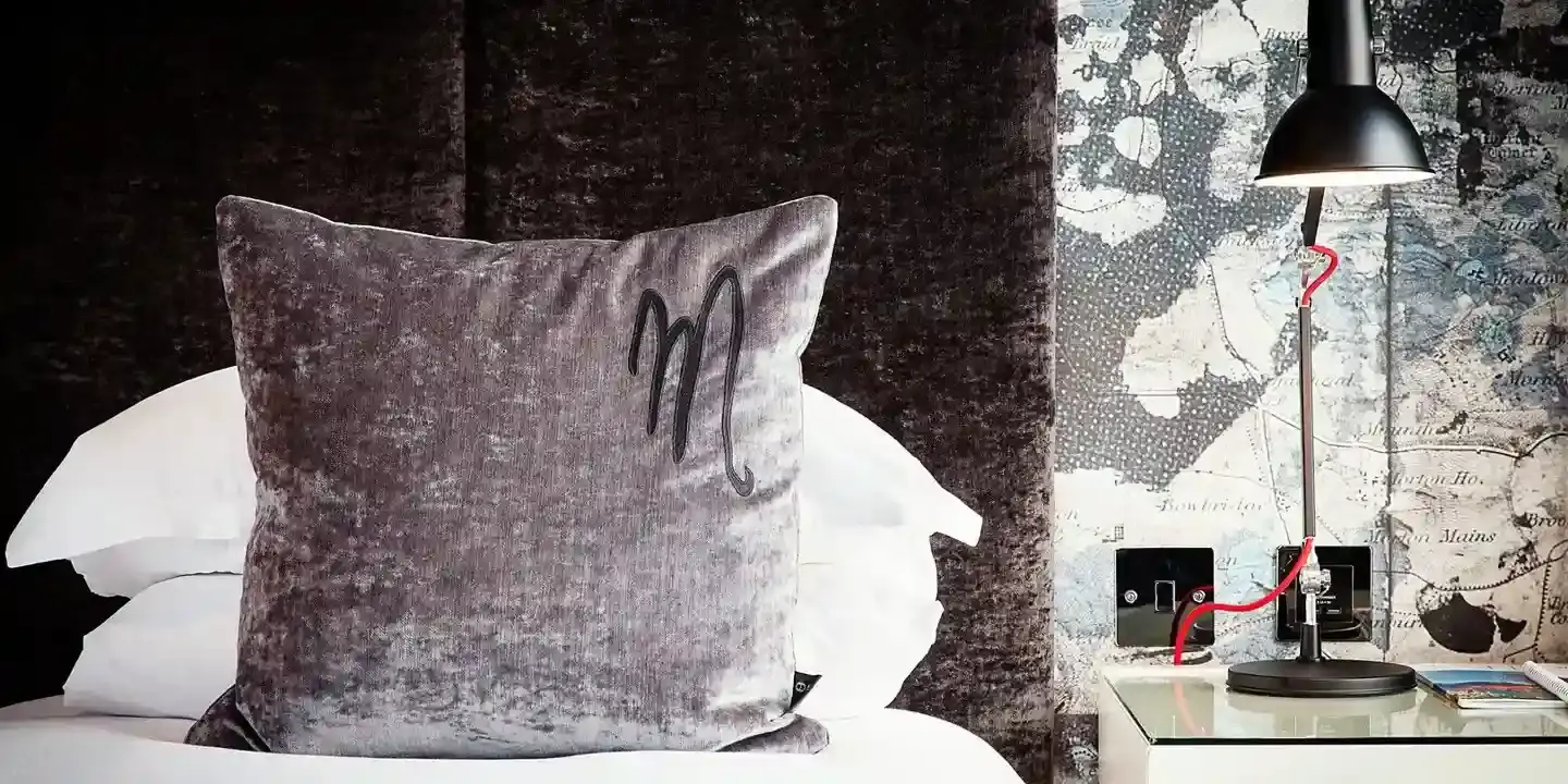 Grey velvet pillow on a bed.