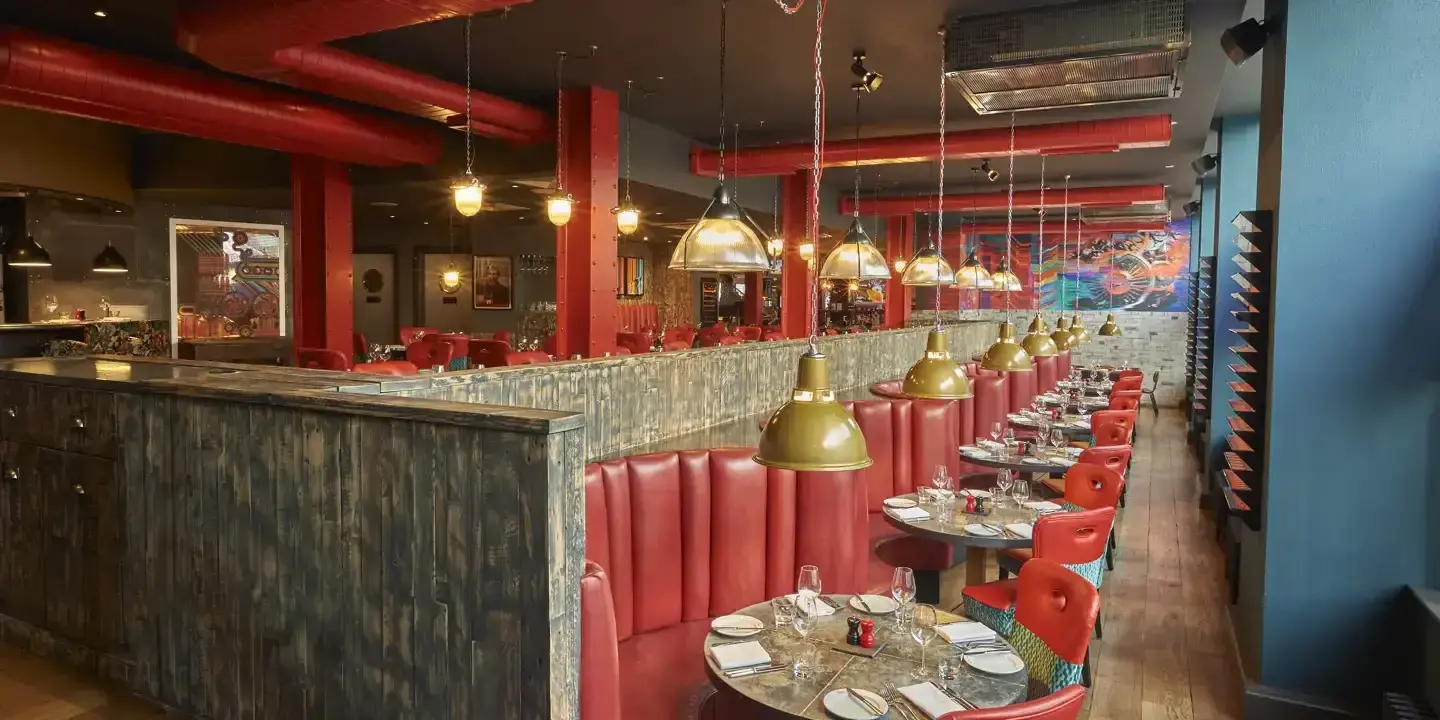 A restaurant featuring red booths and tables.