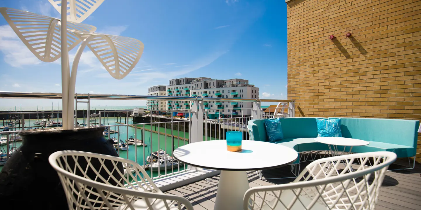 Balcony view of a harbor with a table and chairs.