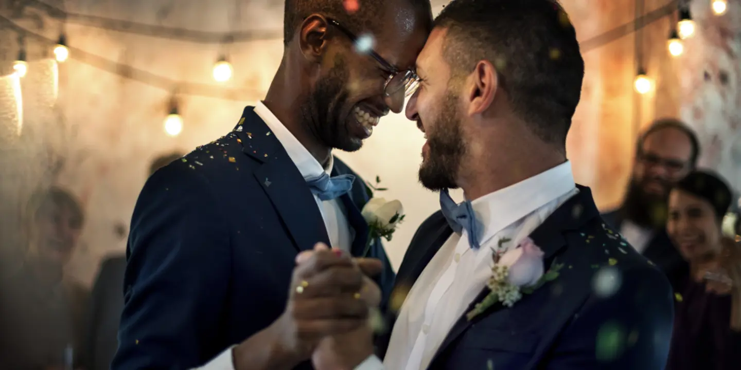 Two men dancing with each other as confetti falls on them.