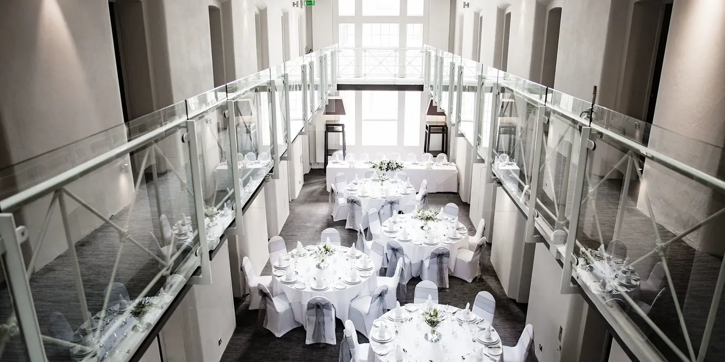 A room adorned with white tablecloths draped over tables.