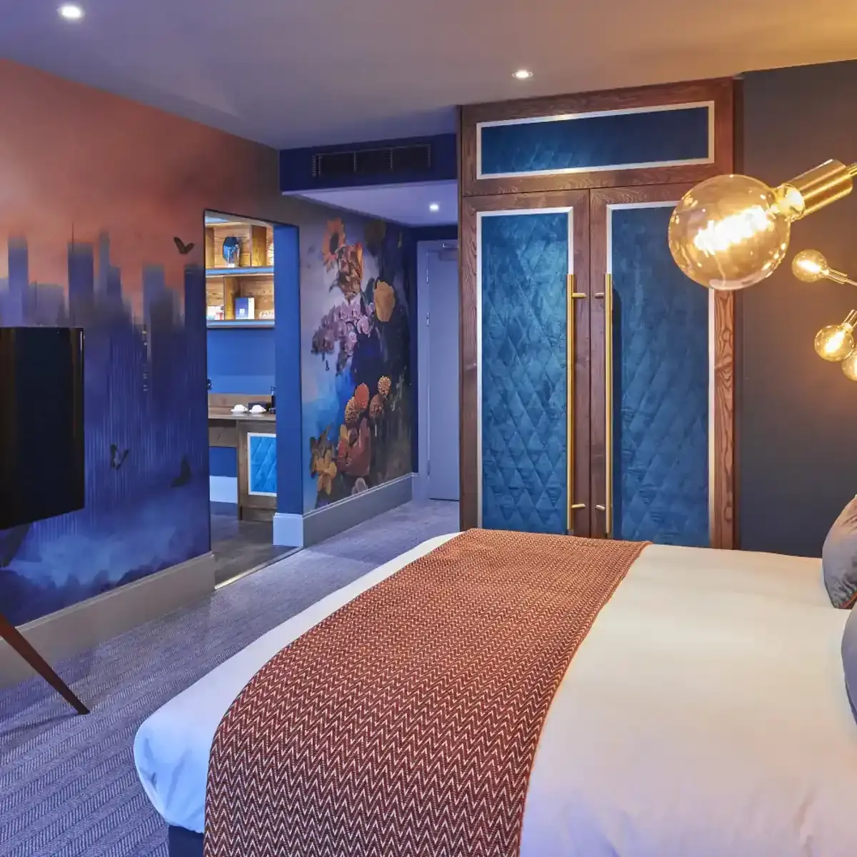 A hotel suite with a bed, wardrobe, and blue decor