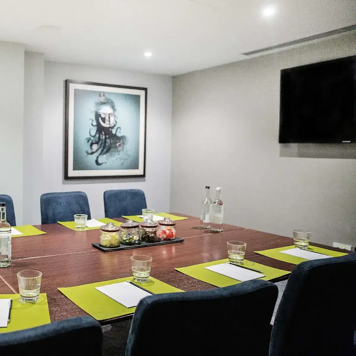 Malmaison Birmingham W+P Meeting room with table and seats visible, green place settings, writing pads, and feature jars of boiled sweets