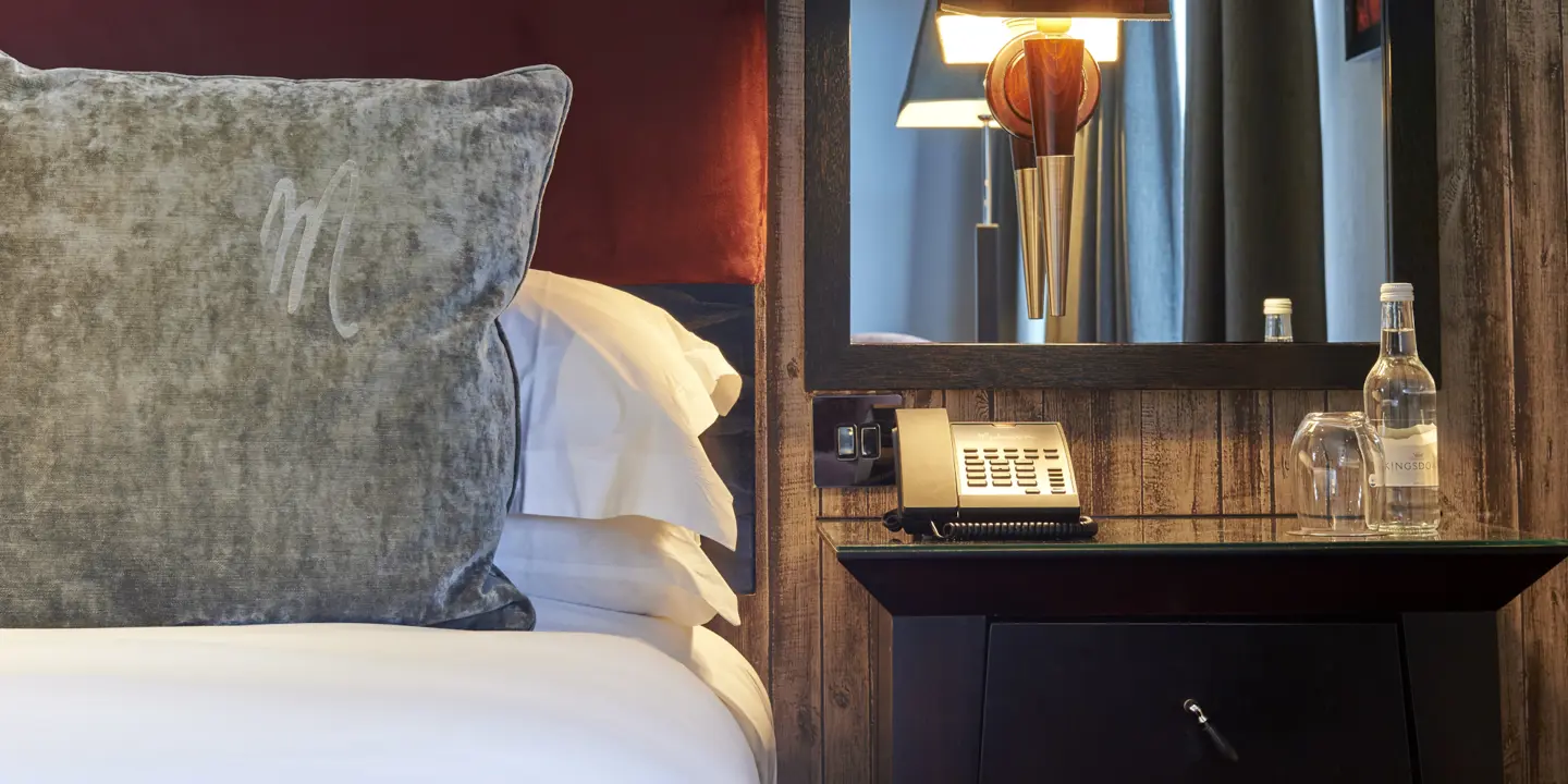 Hotel room featuring a neatly made bed and a telephone placed on the nightstand.