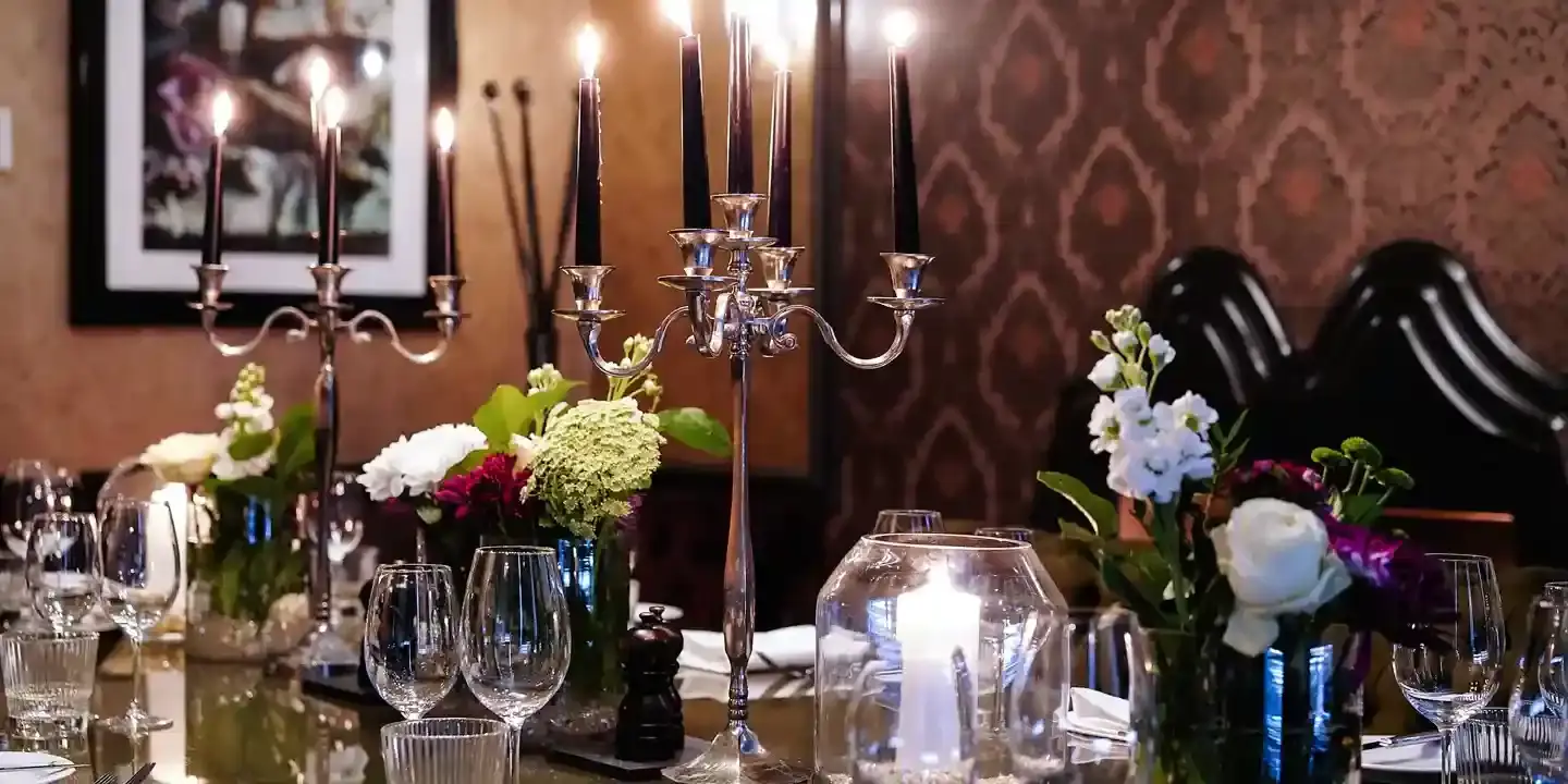 A table adorned with a beautiful vase filled with flowers and accompanied by flickering candles.