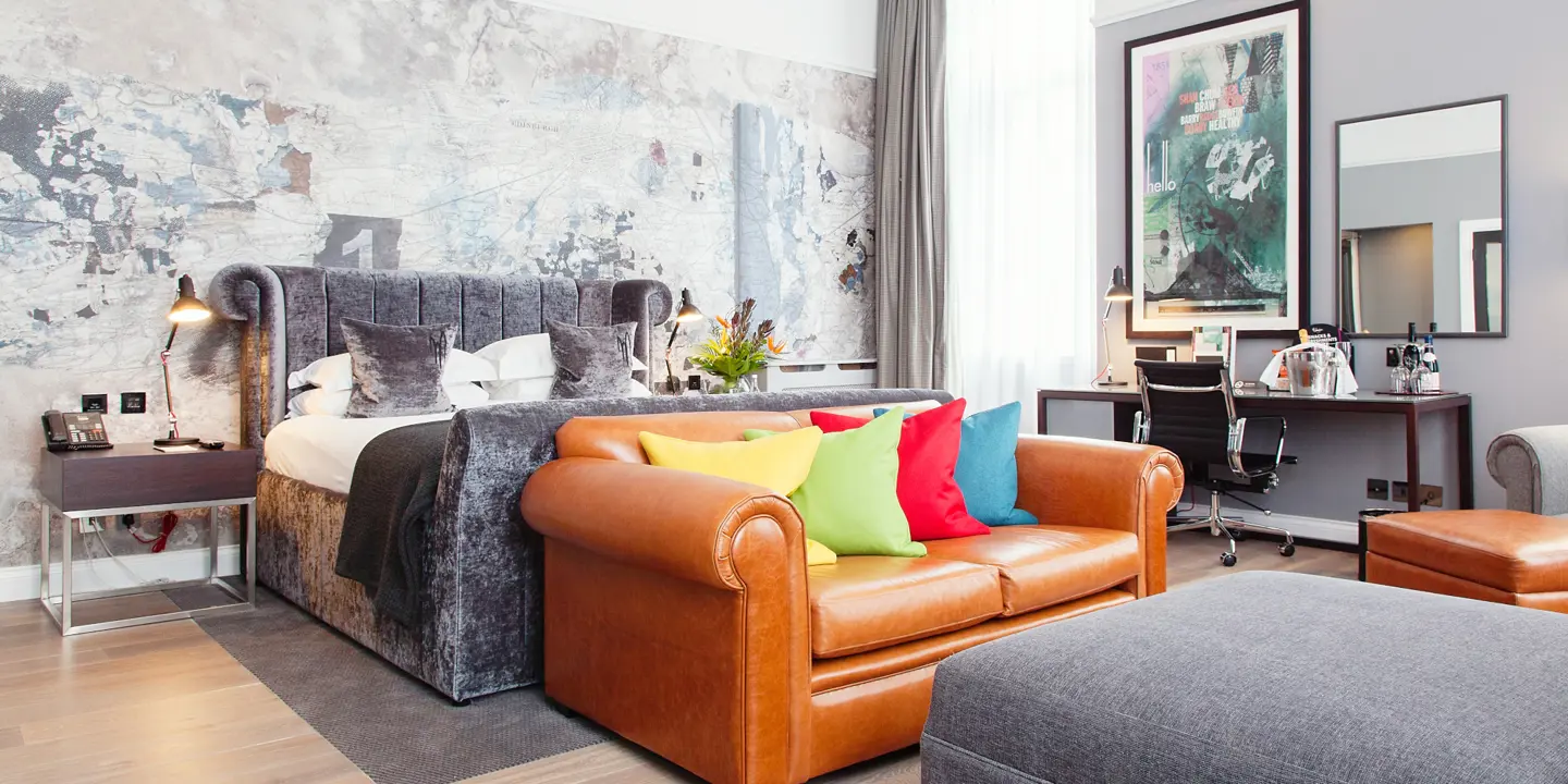 A well-furnished room featuring a brown leather sofa and a bed.
