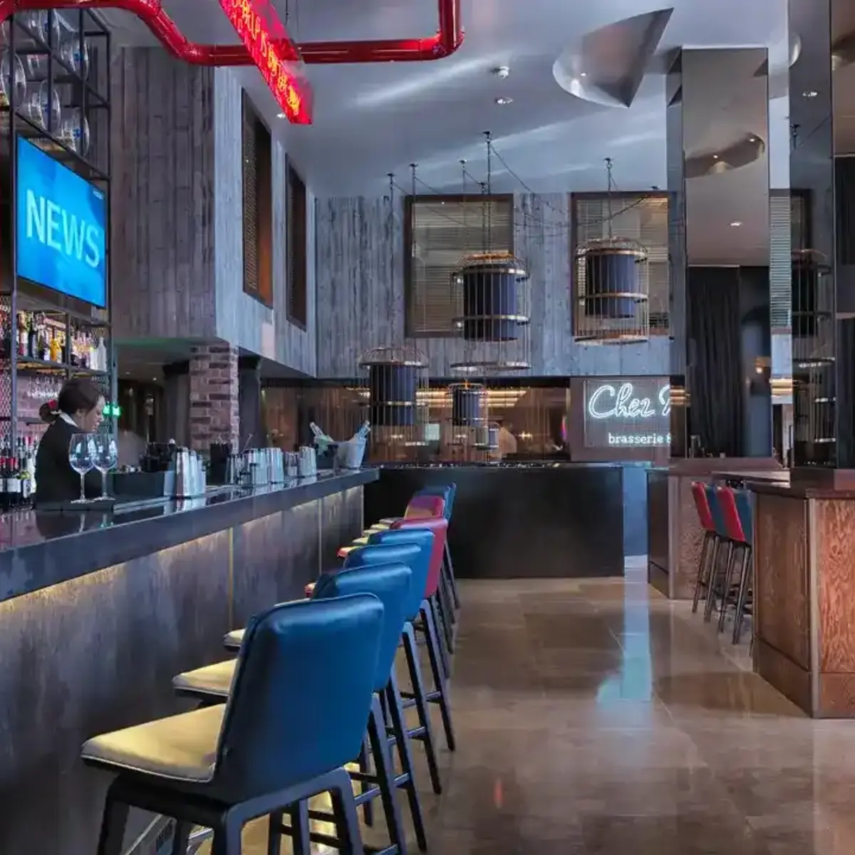 Birmingham Malmaison bar with grey granite bar top, leather stools lining the bar and several tables with seating are visible.