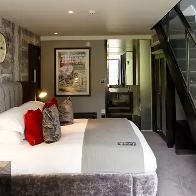An elegantly furnished hotel room featuring a comfortable bed and stylish staircase.