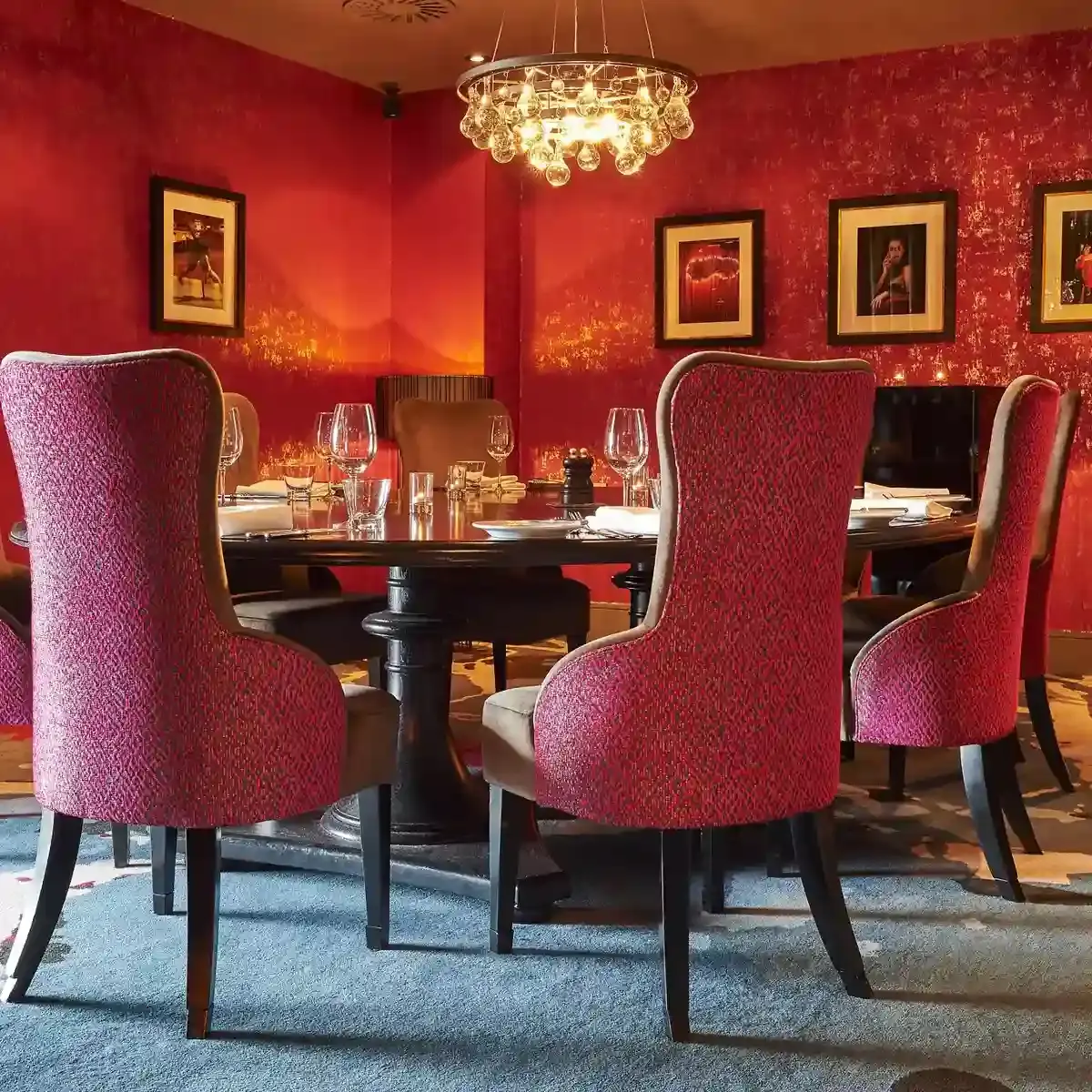 Malmaison Aberdeen Hauf Meeting & Dining room featuring a grand wooden table and high back red fabric chairs with warm overhead lighting.
