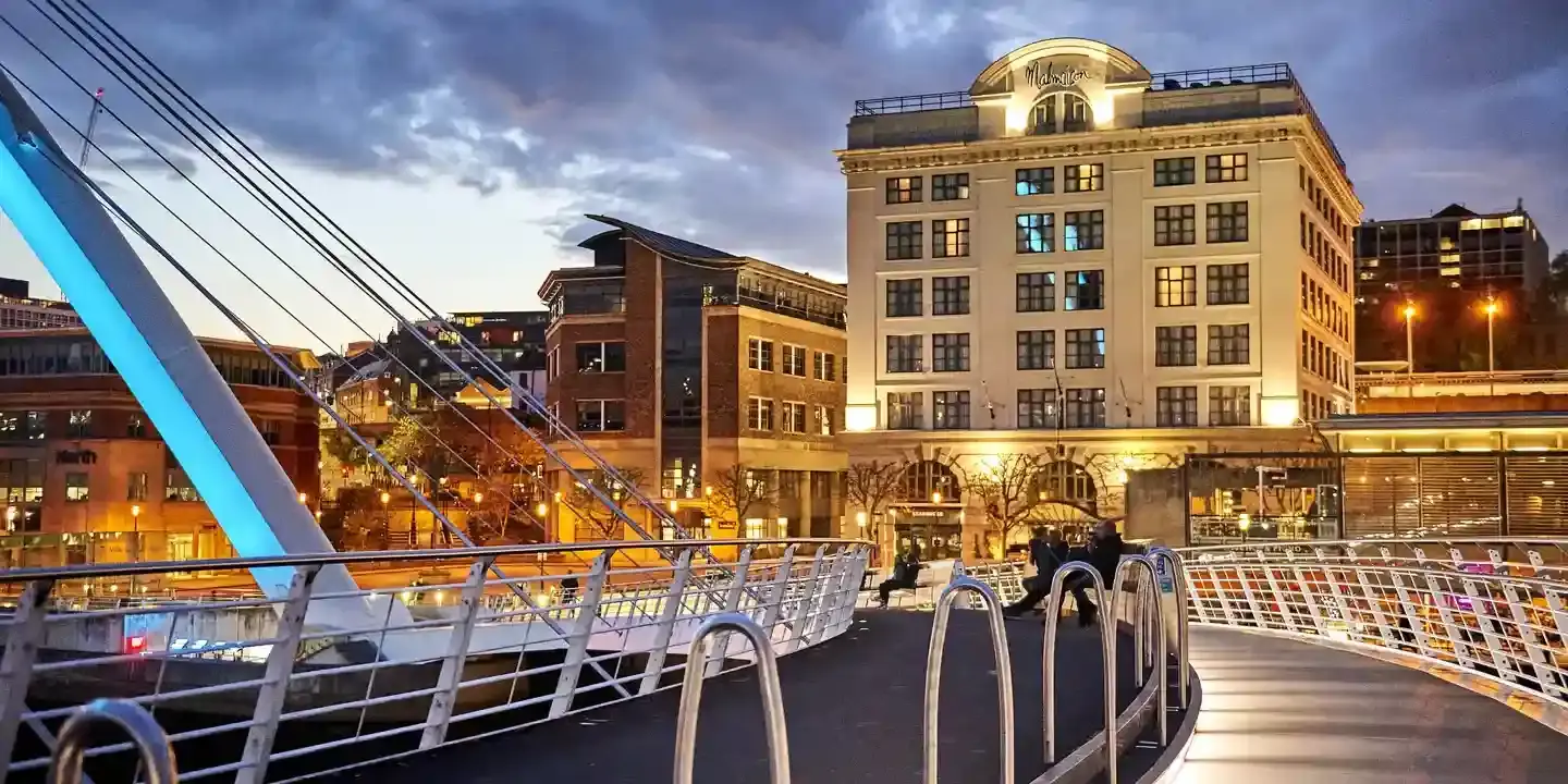 A bridge spanning a river with a well lit building in the background.