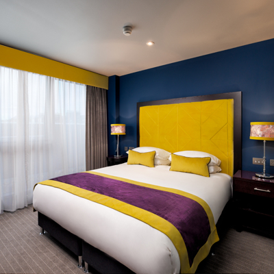 A bedroom featuring a sleek black headboard with tartan print and a desk.
