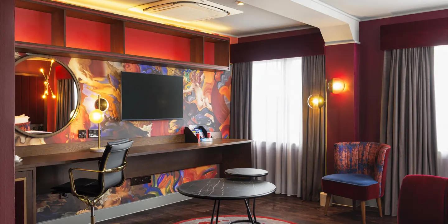 Spacious room featuring a stylish desk, mirror and wall mounted TV.