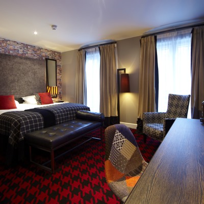 Spacious hotel room featuring a king-sized bed and elegant red carpet.