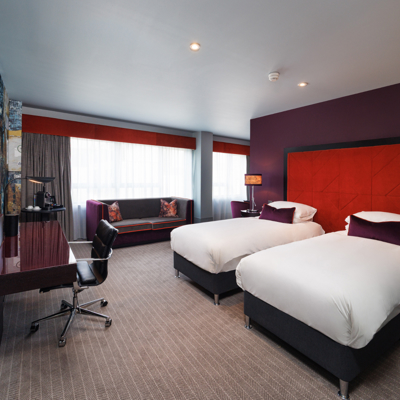 An elegantly made bed adorned with two plump pillows and a stylish lamp.