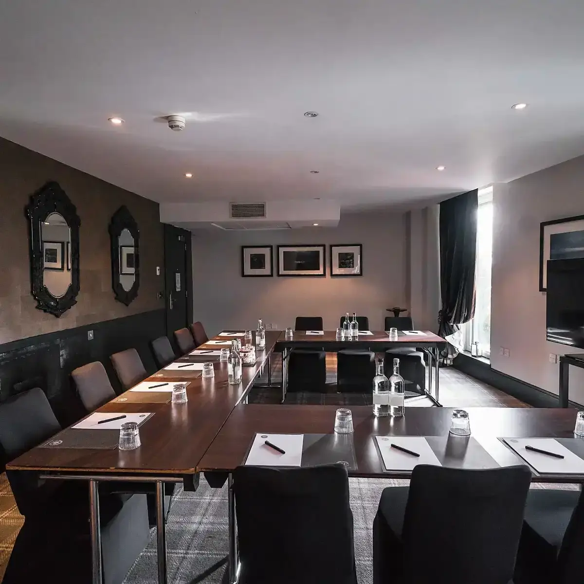 Malmaison Aberdeen Rubislaw Meeting room elegantly furnished featuring a lengthy table adorned with sleek black chairs.