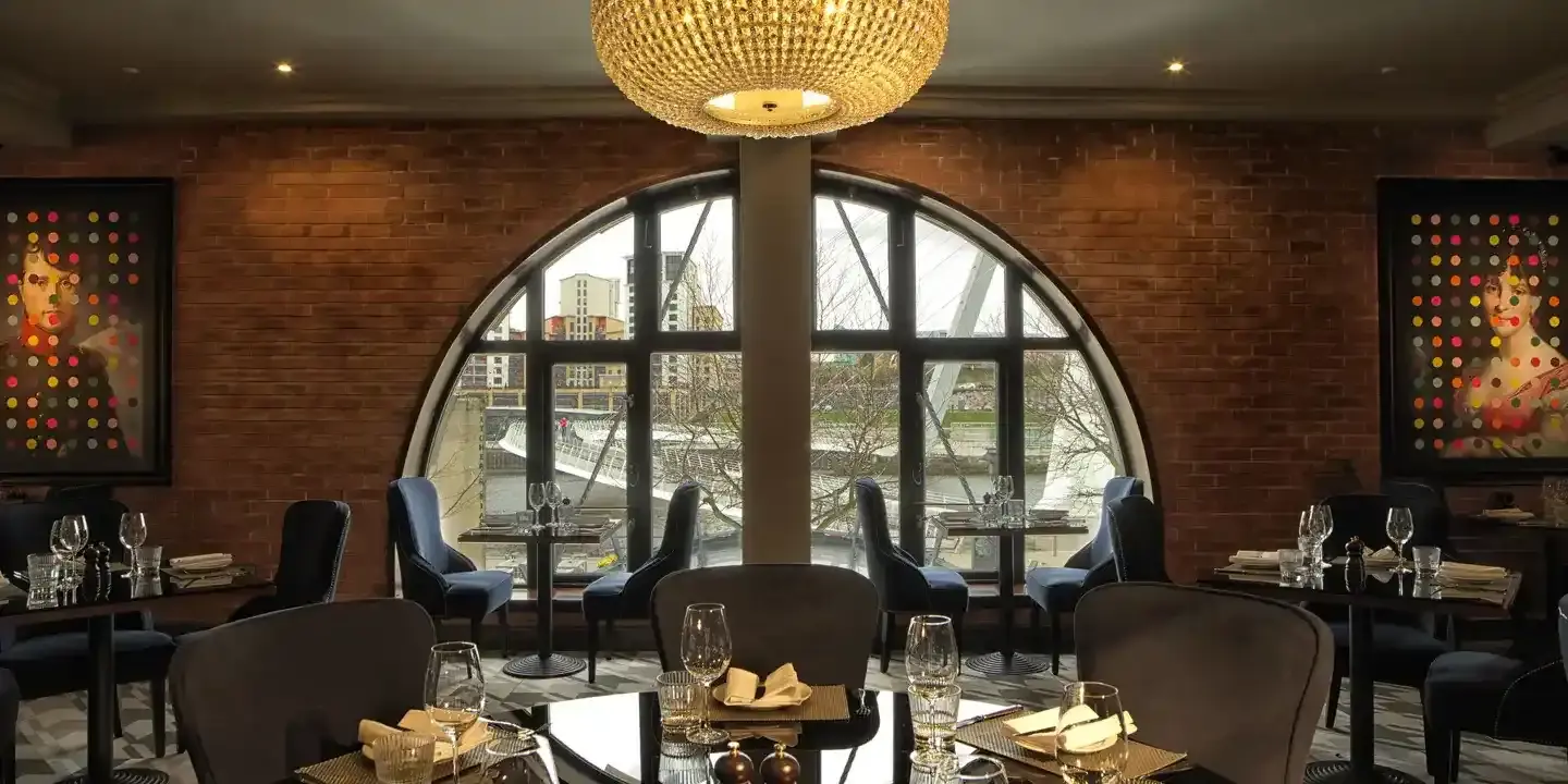 A dining room featuring a chandelier and expansive windows.