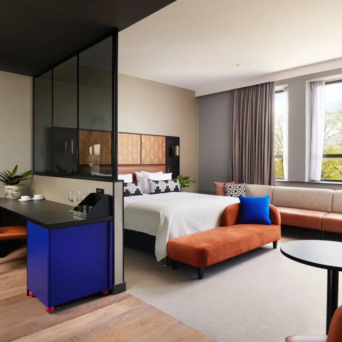 A well-furnished room featuring a comfortable bed, cozy couch, elegant table, and stylish chairs.