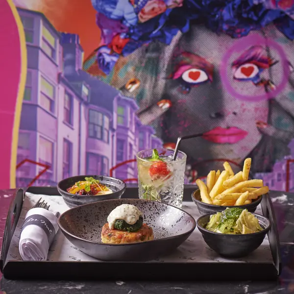 Tray of food displayed on a table in front of a captivating mural.