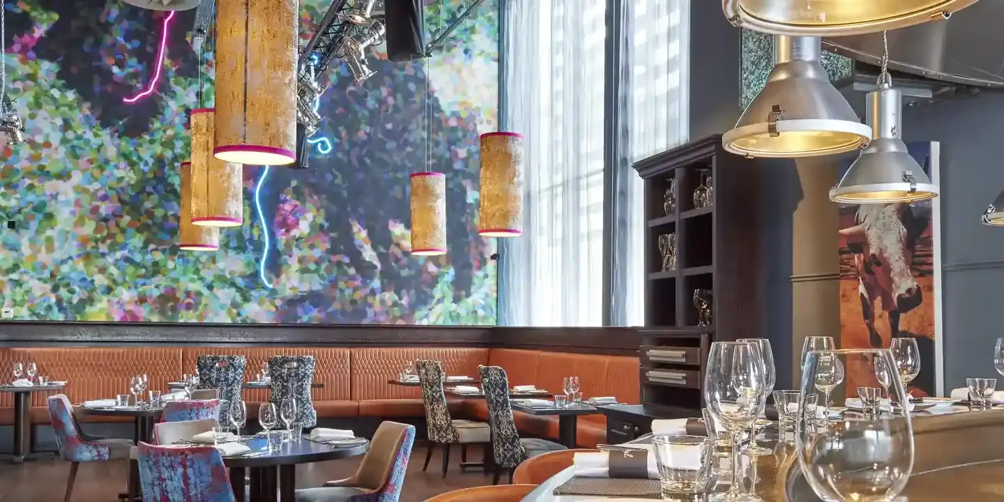 Malmaison Aberdeen Grill dining room, with tables and chairs, bench seating, stool seating at the bar, and featuring a prominent wall painting.