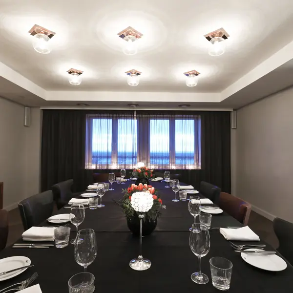 A dining room featuring a spacious table and chairs, feature window and round glass light fixtures.