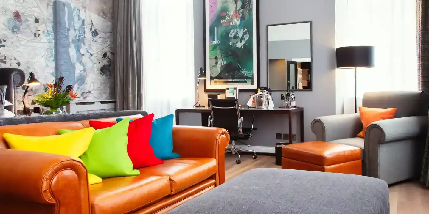 A well-furnished room featuring an orange leather sofa, grey armchair and desk.