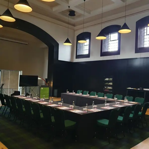 A spacious room featuring a lengthy table adorned with vibrant green chairs.