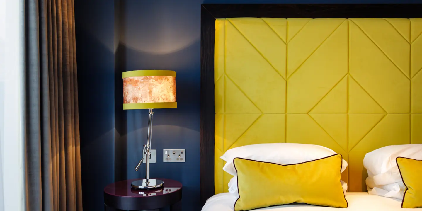 Bedroom with a bed with a tartan headboard and carpet. 