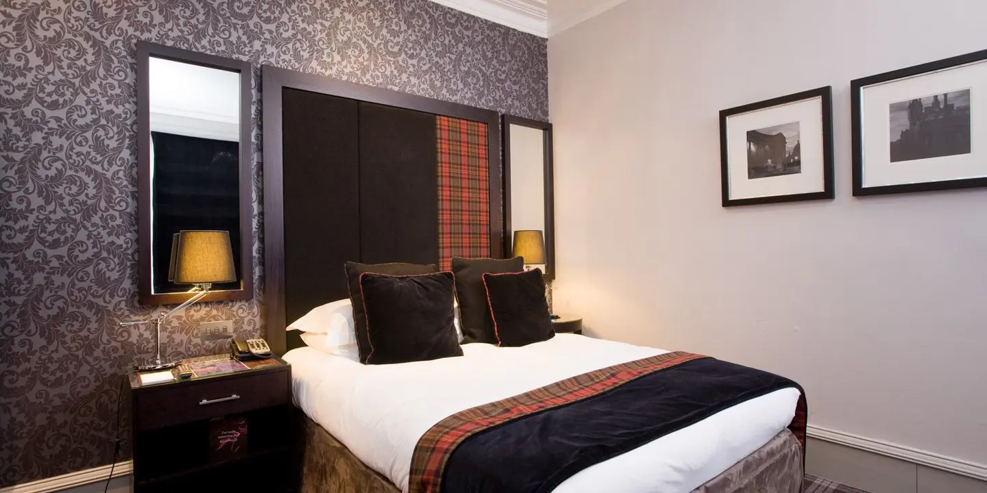 Bedroom with a bed with a tartan headboard and carpet. 