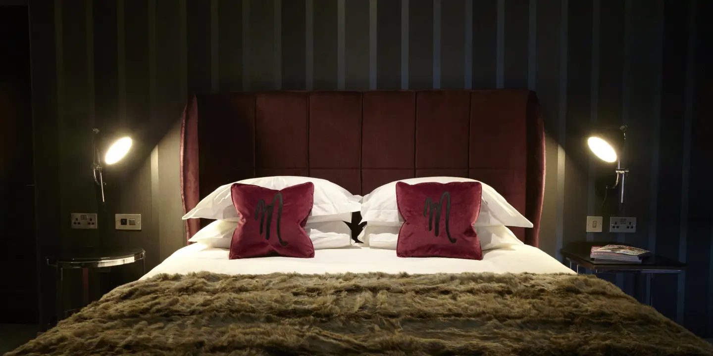 Red velvet bed adorned with two plump cushions.