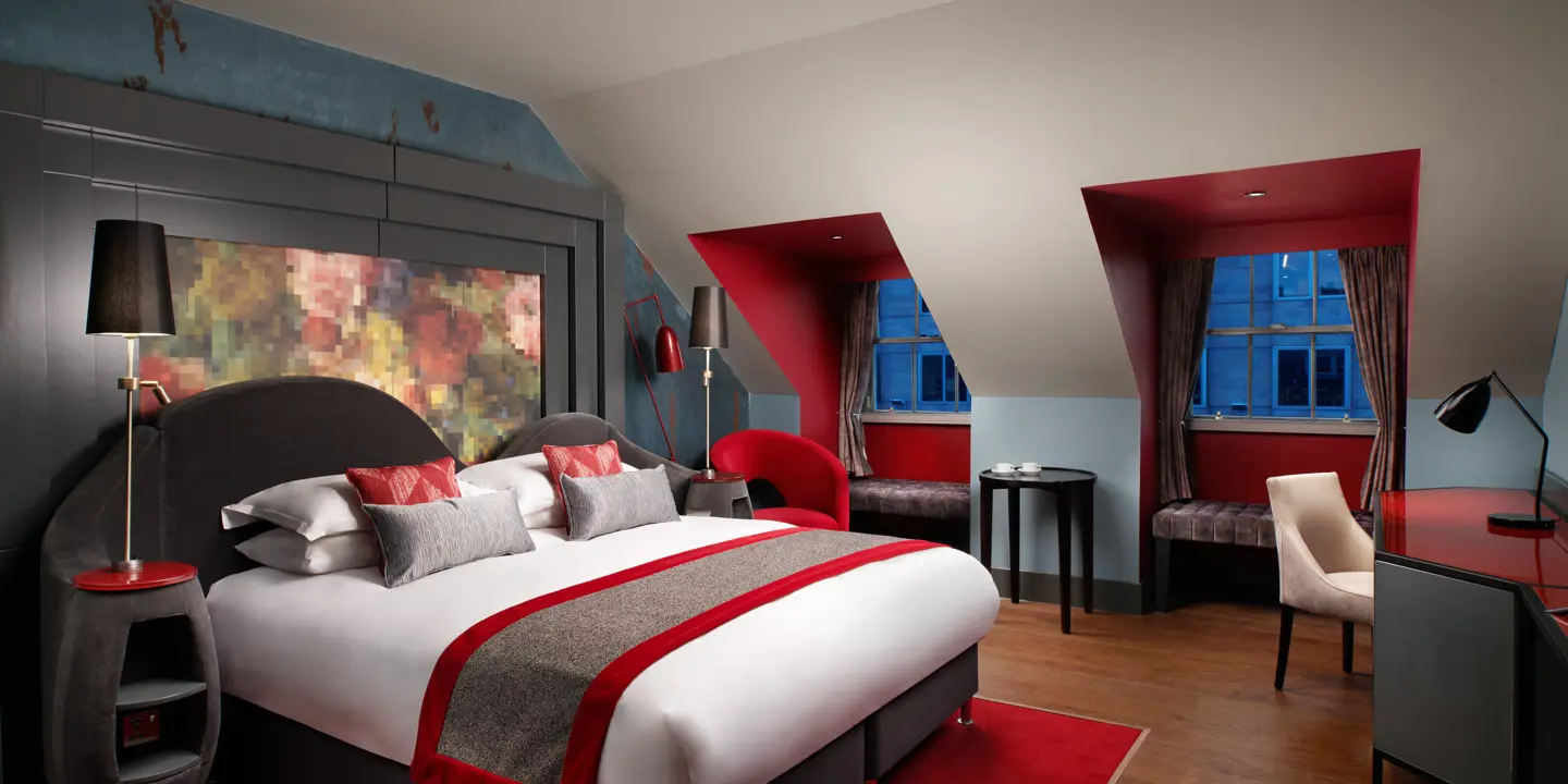 Spacious bedroom featuring a king-sized bed with vibrant red accents.