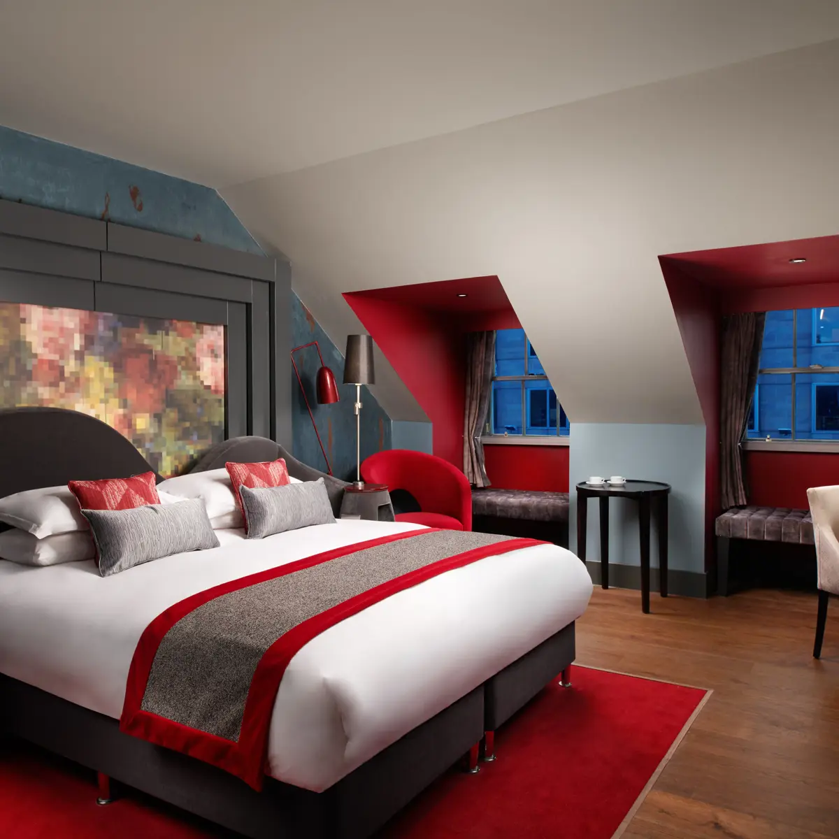 Spacious bedroom featuring a king-sized bed with vibrant red accents.