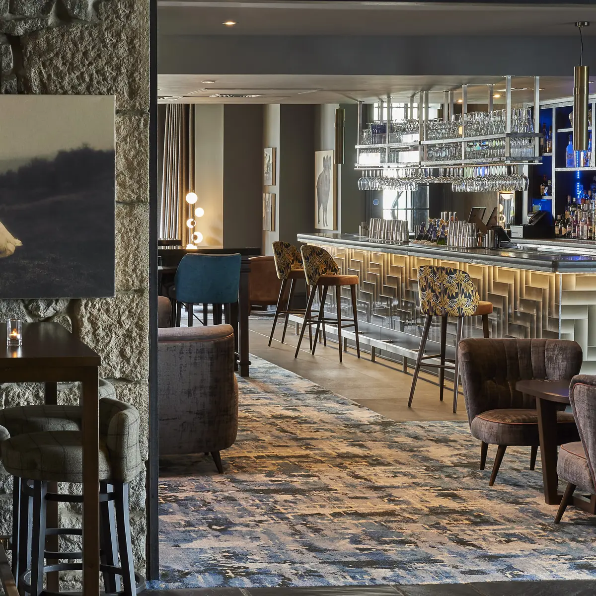 The bar adorned with numerous chairs and tables, and multiple glasses hanging from a ceiling rack
