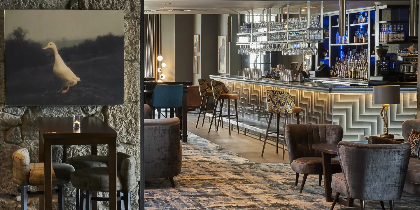 The bar adorned with numerous chairs and tables, and multiple glasses hanging from a ceiling rack