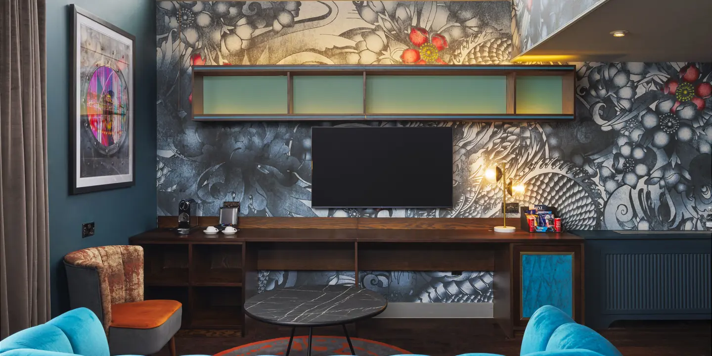 A room featuring a velvet sofa and chair with a wall mounted tv